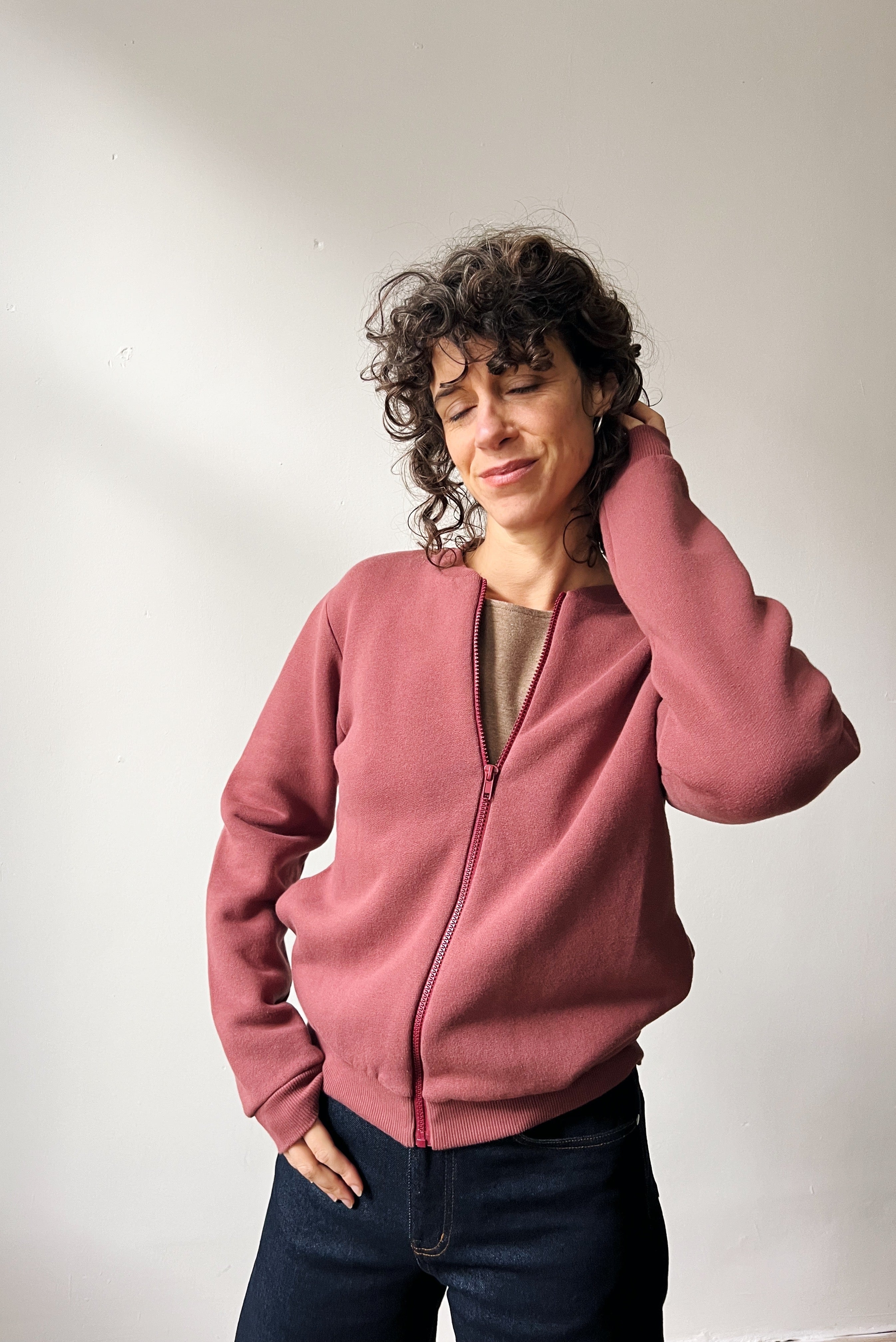 Person wearing a figue bomber against a plain background