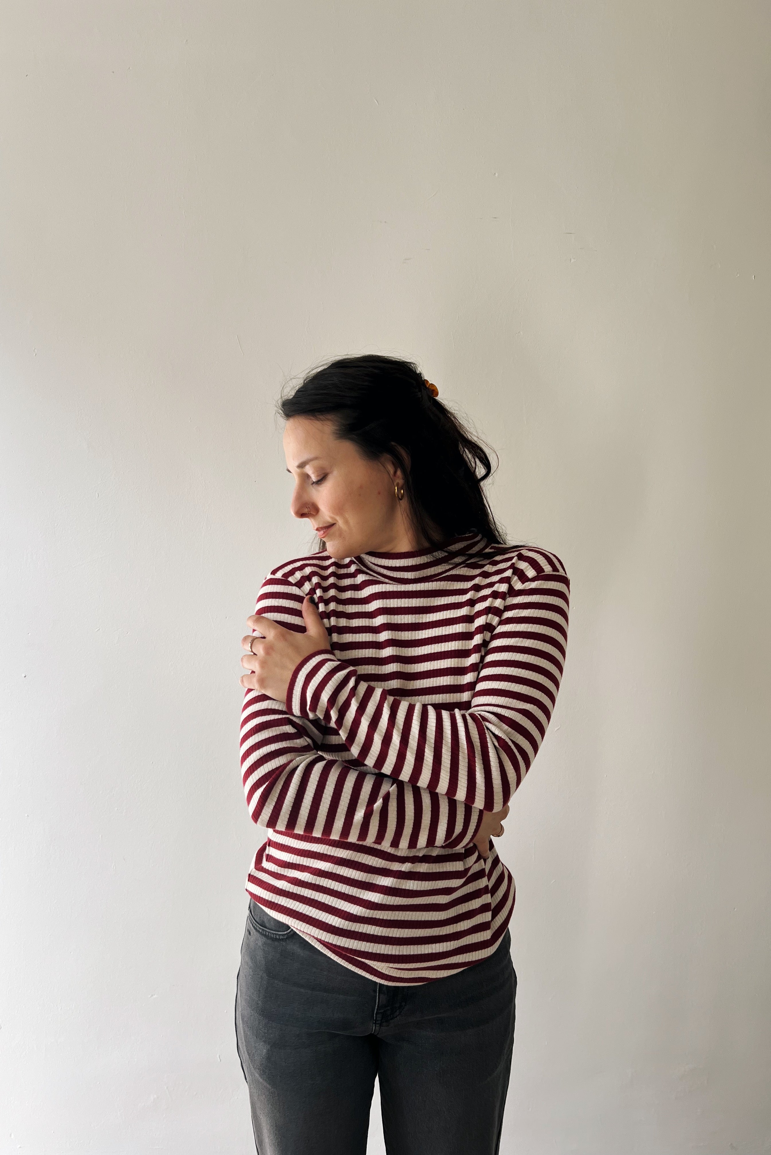 Woman wearing a red and white striped turtleneck against a plain background