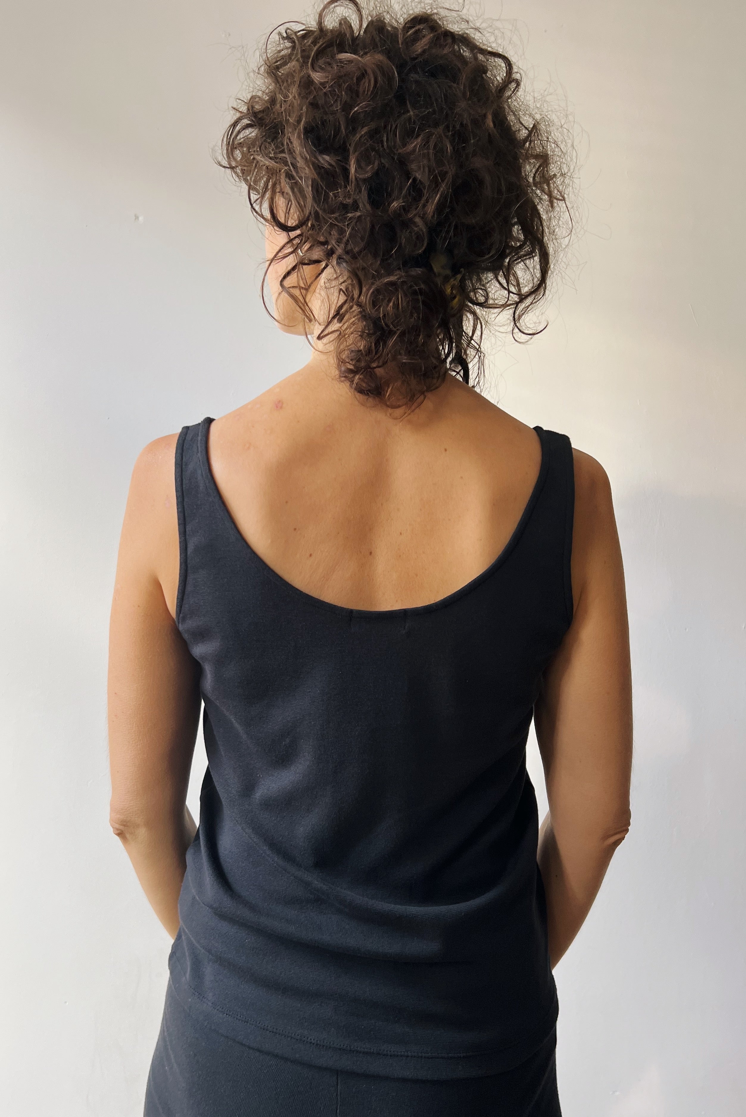 Person wearing a black sleeveless top against a plain background