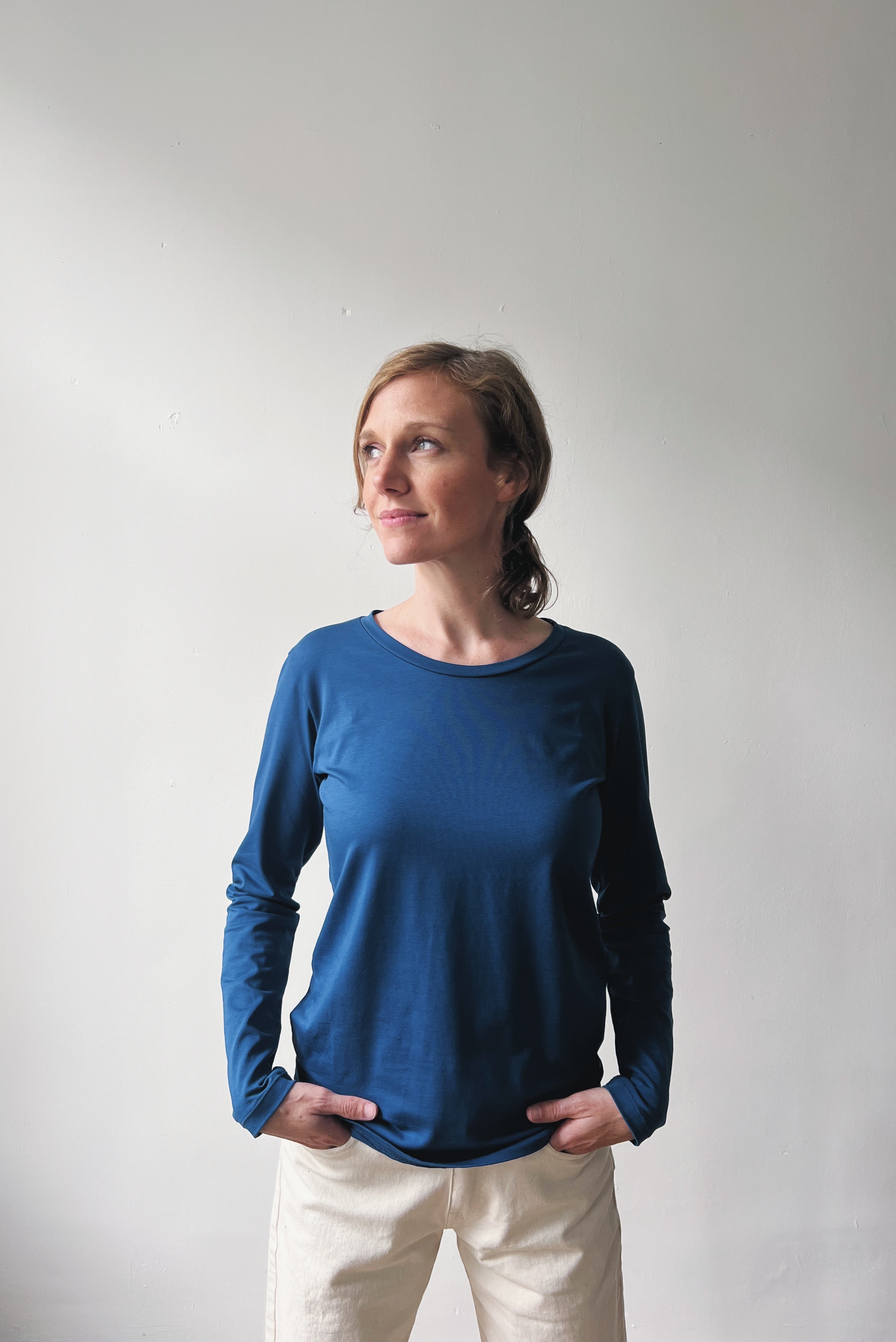 Woman wearing a blue long-sleeve top against a plain background